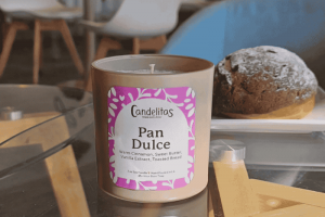 Pan Dulce Scented Soy Candle Next To A Sweet Bread Pastry On A Table.