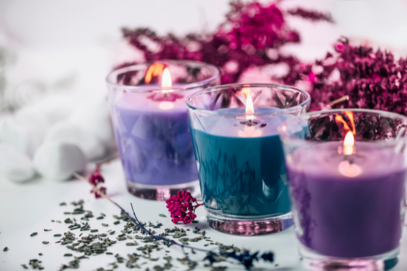Aromatherapy Candles In Purple And Blue Glass Holders Surrounded By Dried Lavender And Flowers, Illustrating The Calming And Mood-Boosting Benefits Of Aromatherapy Candles.